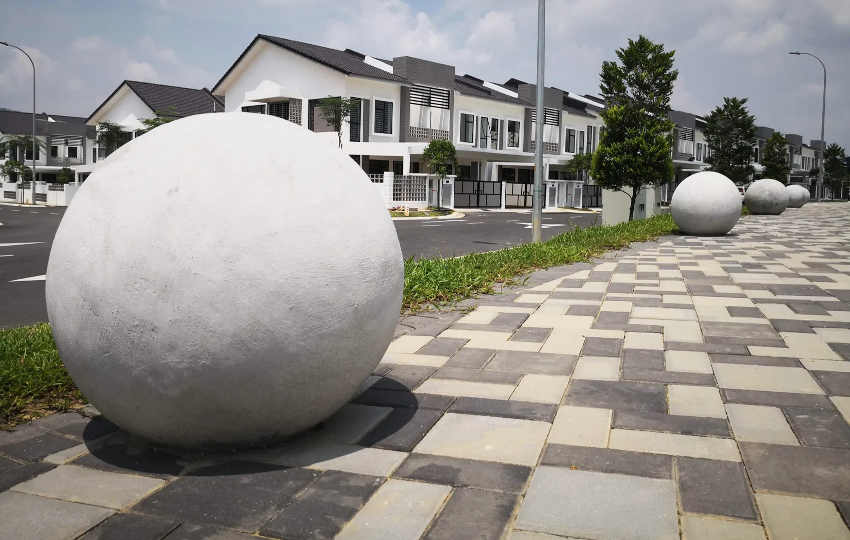 Stone sphere bollards along a paved walk at Serintin