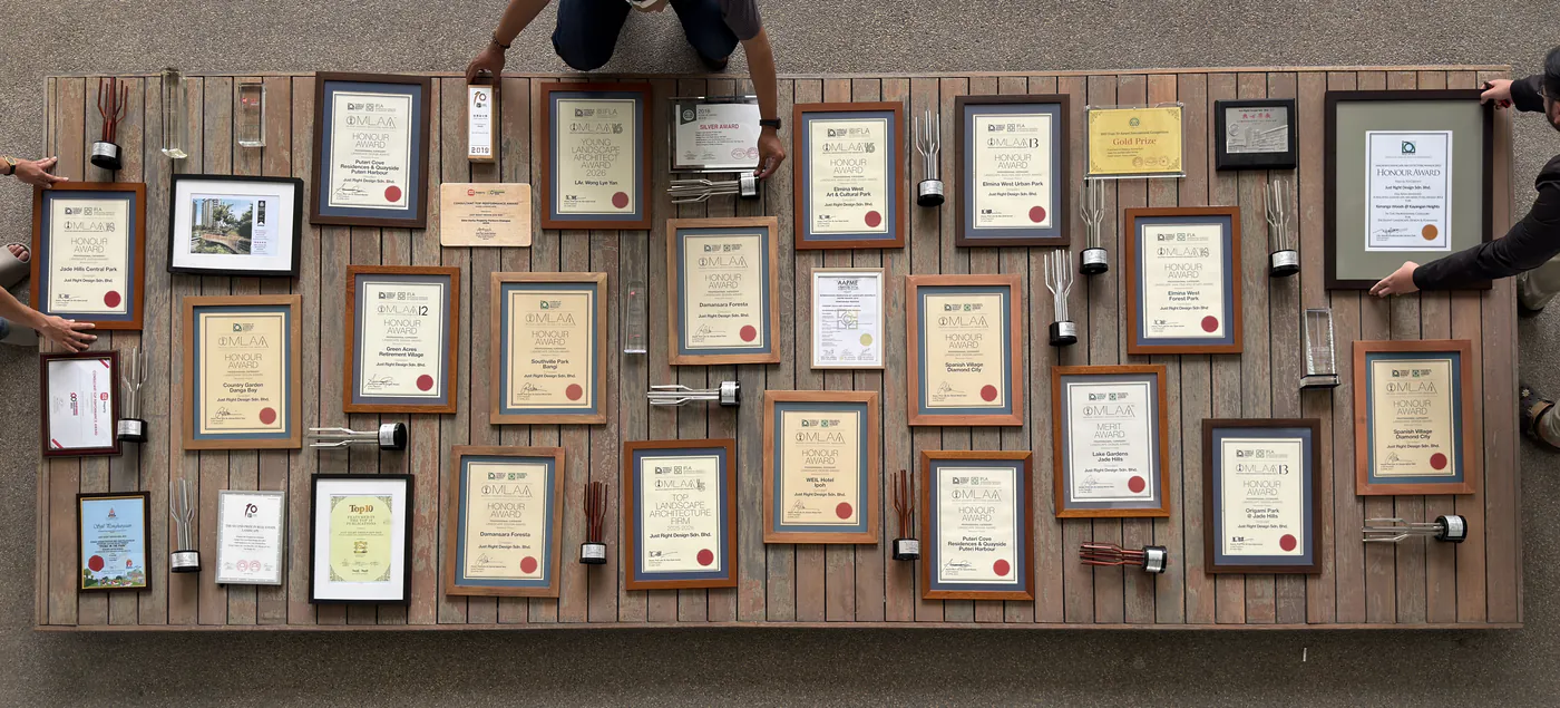 Just Right Design's award certificates and trophies laid out together on a timber table, seen from above